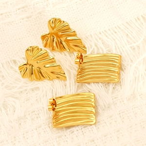 Macro shot of gold leaf earrings and rectangular studs with textured metal relief