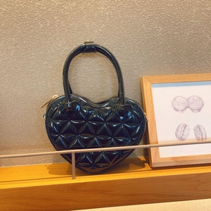 Detail of black heart-shaped quilted PVC jelly bag displayed on a wooden shelf