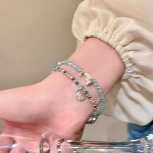 Detail eines Perlenarmband-Sets mit Muschel- und Mondanhängern für den Strandurlaub