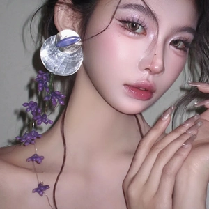 Detail of elegant silver tassel earrings with purple bead clusters worn by a model