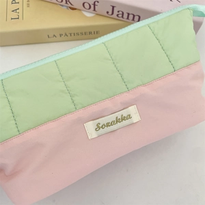 Macro detail of quilted stitching and pastel two-tone fabric on large stationery bag
