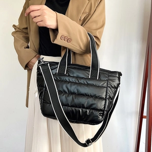 Chic black quilted puffer crossbody bag with striped strap worn by model for daily style