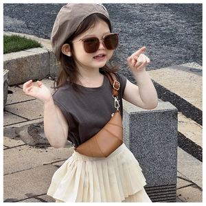 Toddler modeling a brown croissant crossbody bag in a natural outdoor stone setting