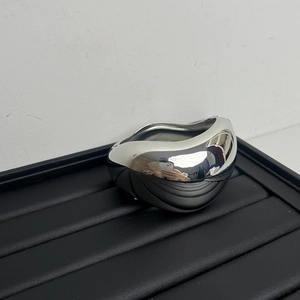 Nahaufnahme eines silbernen geometrischen Metallarmbands mit glatter Spiegeloberfläche
