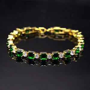 Detail of gold tennis bracelet with square green and round clear cubic zirconia stones