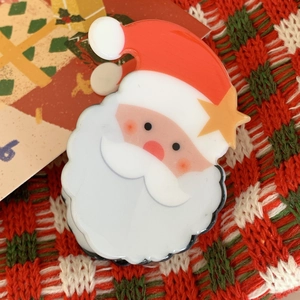 Close-up of a Santa Claus acrylic hair claw clip on festive red and green knit fabric
