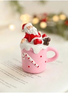 Close-up of Santa Claus resin figurine in pink mug with snowy detail on book page