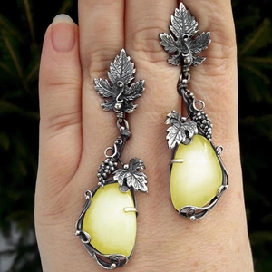 Macro shot of vintage silver vine leaf earrings with white teardrop opal on hand