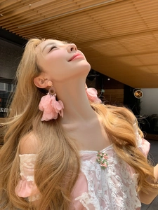 Détail des boucles d'oreilles fleurs en tissu rose portées par un mannequin chic