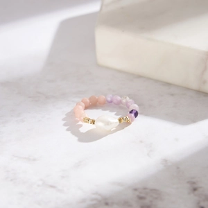 Detail of stretch ring featuring pink opal, purple beads and a white freshwater pearl