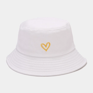 Détail d'une broderie cœur jaune sur un bob en coton blanc avec bord surpiqué