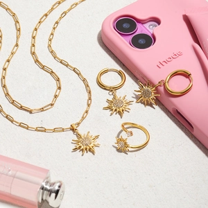 Detailed shot of golden sun-shaped necklace, earrings, and ring set with rhinestones