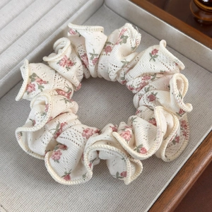 Detailed close-up of cream floral lace scrunchie with pink flowers in a wooden tray