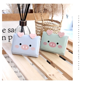 Detail of cute pig cartoon trifold wallets in blue and green with heart accents