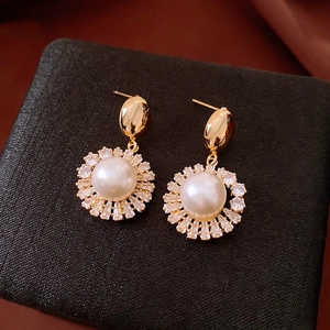 Detailed close-up of French vintage gold-plated earrings with round pearls and shiny zircons