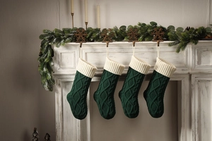 Detail of four dark green knitted Christmas stockings hanging on a white fireplace mantel