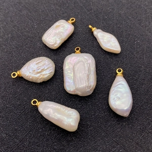 Macro detail of assorted baroque pearl pendants with gold bails on a black mesh background