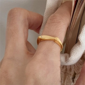 Close-up of golden brushed 925 sterling silver ring with a sparkling zircon on a hand