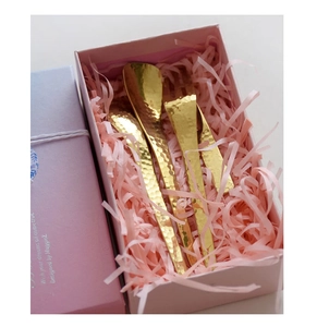 Macro shot of gold hammered stainless steel cutlery set in a pink gift box
