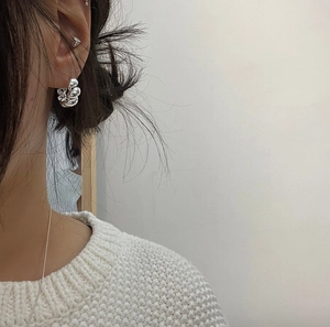 Detailed view of silver twisted hoop earrings with a textured lava finish on a model