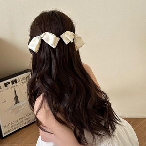 Elegant white rhinestone bow hair clips for women on wavy hair from a back view