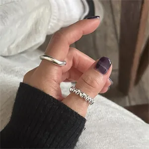 Close-up of 925 sterling silver wavy and twisted rope ring set worn on a finger