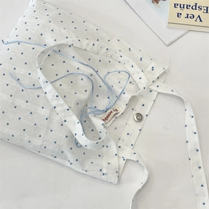 Detailed shot of canvas tote bag showing heart print, magnetic closure and shoulder strap