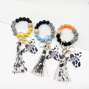 Detail of mama cow print silicone bead keychains with wooden charms and tassels