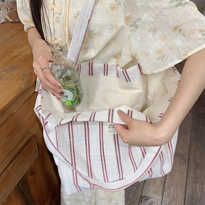 Detail showing the large capacity of the striped canvas tote bag with a water bottle