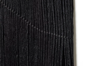Macro shot of black velvet dress halter fringe showing dense woven details and texture
