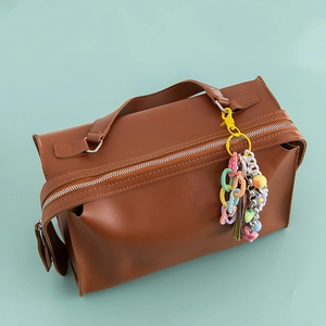 Close-up of brown faux leather handbag with a colorful tassel keychain and heart bead