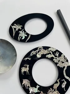 Detailed view of handcrafted lacquer hairpins with iridescent shell inlay and pine motifs