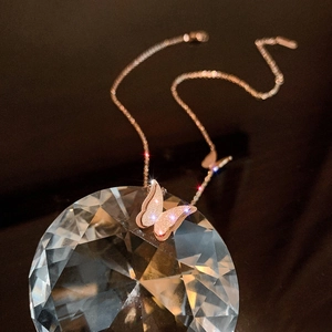 Rose gold butterfly pendant necklace with frosted wings on faceted crystal display