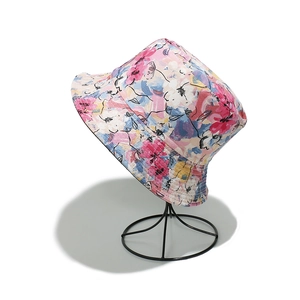 Detail of a floral bucket hat with colorful abstract patterns on a black metal hat stand