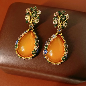 Detailed macro view of vintage gold earrings with orange gemstones on leather background