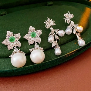 Détail macro de boucles d'oreilles fleurs en perles et puces étoiles avec pierre verte