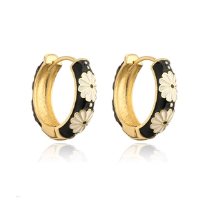 Close-up of golden hoop earrings with black enamel and delicate white daisy floral pattern