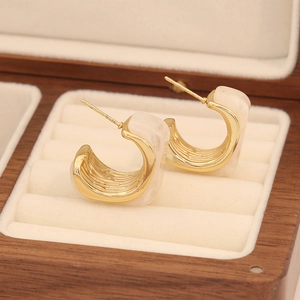 Détail macro de boucles d'oreilles vintage en résine ambrée en forme de C en bois