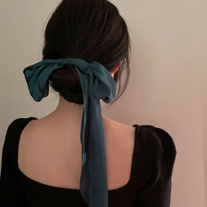 Rear view of a model wearing a dark green satin bow hair ribbon for elegant styling