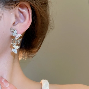 Detailed view of silver butterfly tassel earrings with shell inlay and zircons on model