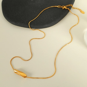 Minimalist gold necklace featuring a twisted cylindrical pendant on light background