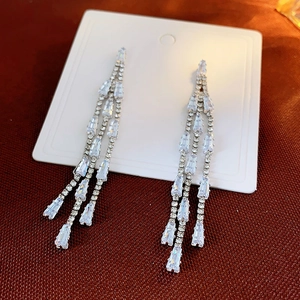 Detail view of long silver tassel earrings with tiered baguette-cut cubic zirconia crystals