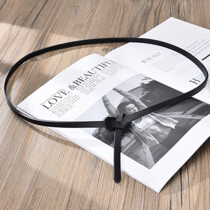 Slim black leather waist belt for women with minimalist knot design on magazine