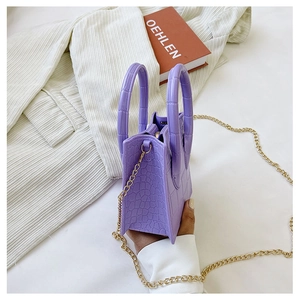 Macro detail of purple crocodile-patterned crossbody bag with elegant golden chain strap