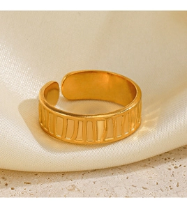 Macro di un anello geometrico placcato oro con strisce verticali su sfondo di seta