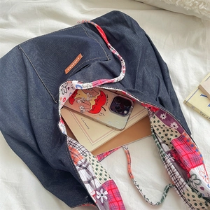 Detail of dark blue denim tote bag with colorful patchwork lining and leather logo tag