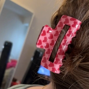 Détail d'une pince à cheveux rose avec motifs de cœurs rouges portée en queue de cheval