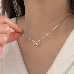 Detail of silver double-loop necklace with transparent bead on a model neck