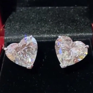 Macro shot of heart-cut zircon stud earrings in a velvet jewelry box with claw setting