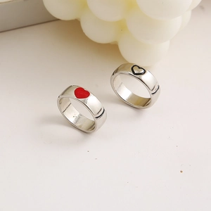 Close-up of silver couple rings set with red and black heart designs on a white background